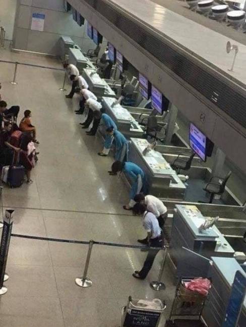 Egy japán légitársaság személyzete, amint épp elnézést kér az utasoktól a járatkésés miatt.