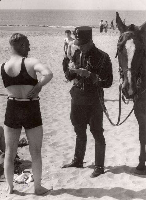 Egy holland lovasrendőr, amint épp bírságot szab ki erre a „nem megfelelően öltözködő” férfira, 1931-ben.