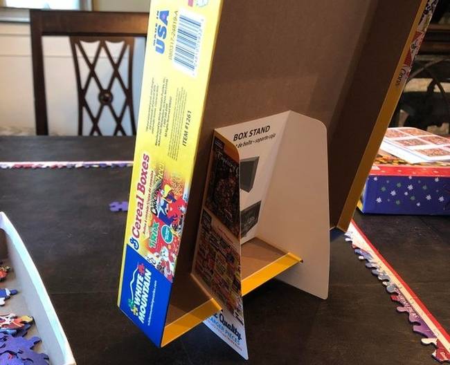 Egy kirakós, amihez egy rögtönzött tartóállványt is csomagoltak, hogy megtartsa a játék dobozát, ezáltal pedig könnyebb legyen a puzzle kirakása.
