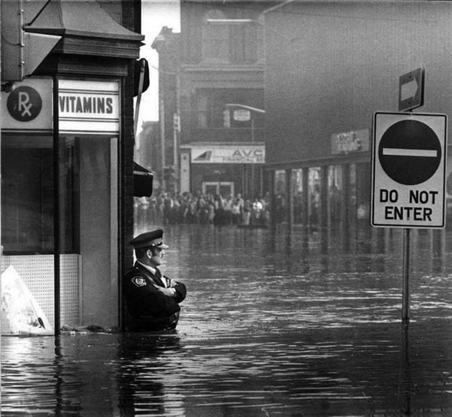 Gyógyszertárat őrző rendőr az elárasztott utca közepén - Ontario, Kalifornia, 1974.