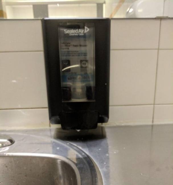 Egy szappanadagoló, amit előrelátóan úgy helyeztek el, hogy véletlenül se férjen be alá a kezünk.