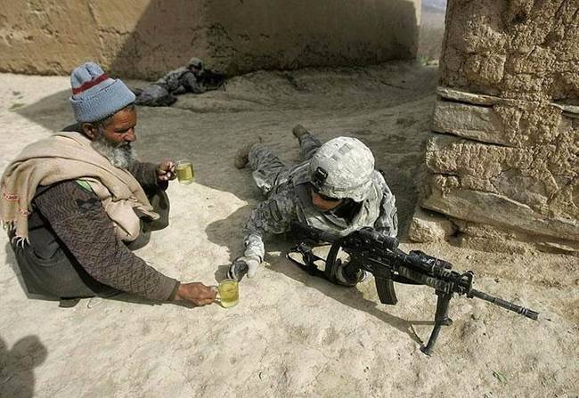 Egy afgán férfi, aki teával kínálja ezt az amerikai katonát.