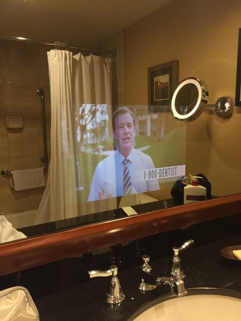 Egy hotel fürdőszobája, ahol a TV a tükörbe beépítve található.