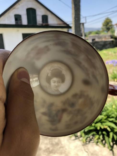 Egy porcelán csésze, aminek az alján egy női alak látható, ha fény felé tartjuk.