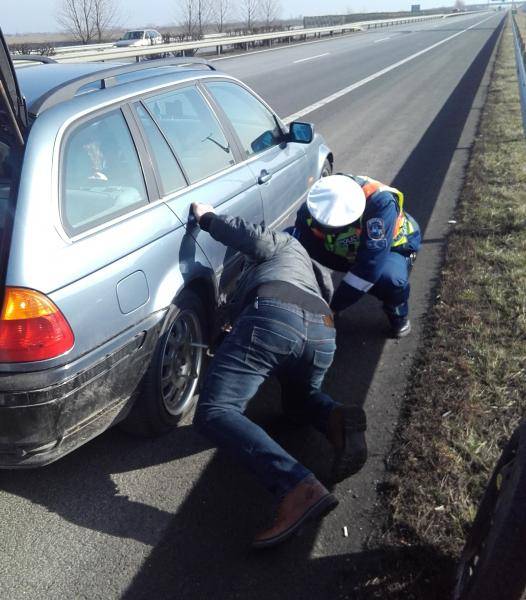 Rendőr segít kereket cserélni az autópályán defektet kapott autósnak.