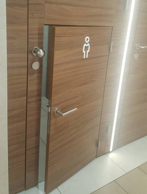 Egy WC-ajtó, amin belül egy külön, kisebb WC-ajtó lett kialakítva a gyermekek számára.