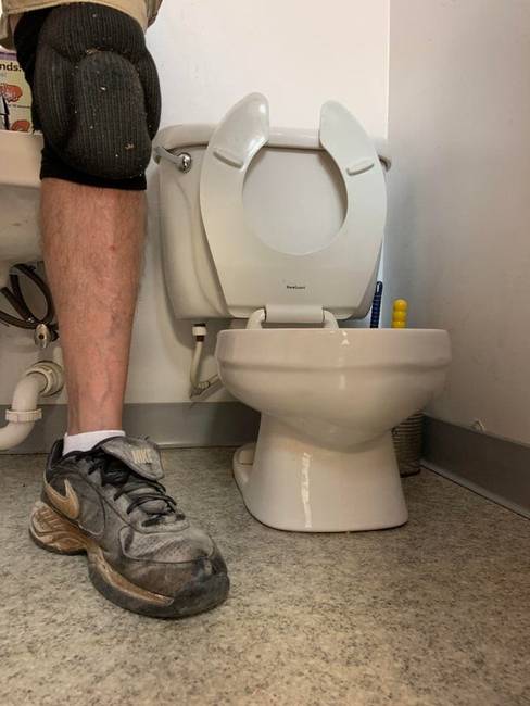 A szerelő férfi lába teljesen normális méretű, pusztán egy óvodai WC látható mellette a képen.
