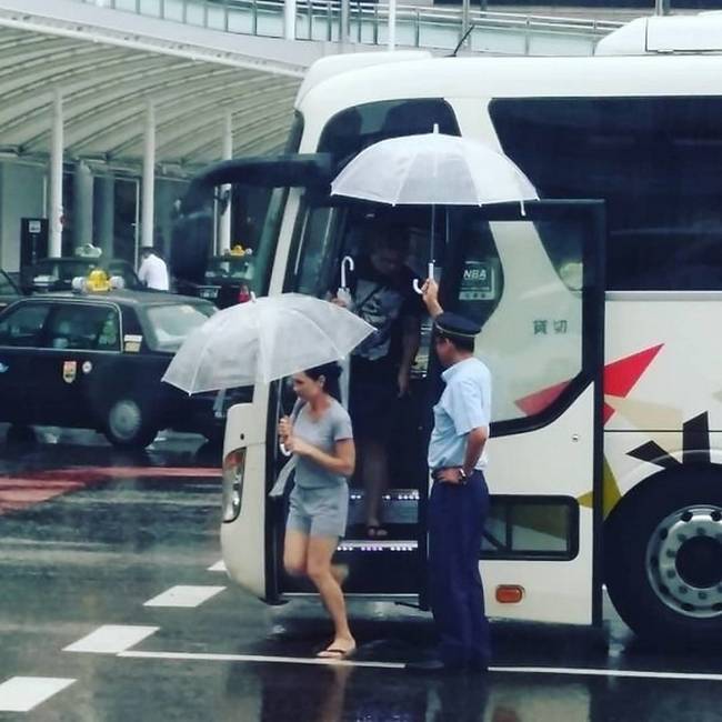 A buszsofőr segít kiszállni az utasoknak egy esős napon.