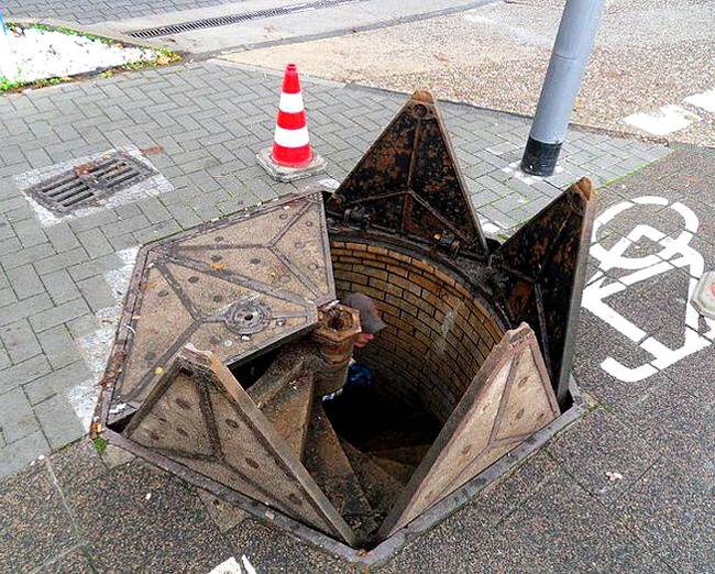 Egy szokatlanul nyíló csatornafedél, csigalépcsővel.