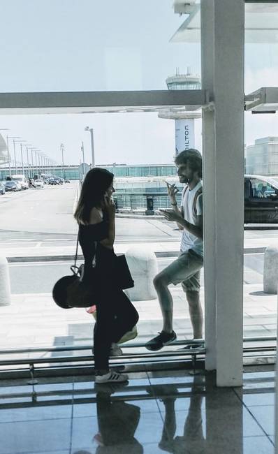 Mielőtt a fiatal pár elbúcsúzna egymástól, még utoljára a reptéri üvegen keresztül a telefonjaik segítségével beszélgetnek egymással.