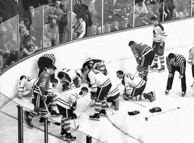 A Toronto Maple Leafs és a Chicago Black Hawks játékosai, amint Jack Evans kiesett kontaktlencséjét keresik 1962-ben.
