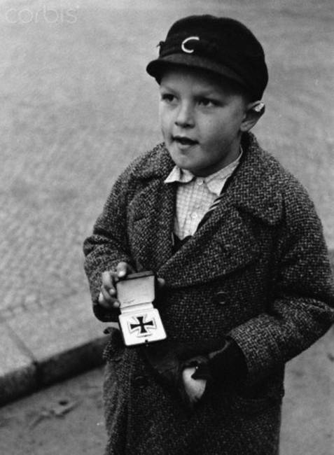 Egy német kisgyerek apja érdemérmét árulja cigarettáért, 1945-ben.