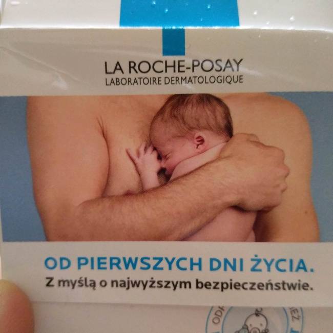 Egy baba krém, amin szokatlan módon az apuka mellkasához szorítva láthatjuk a kisbabát.